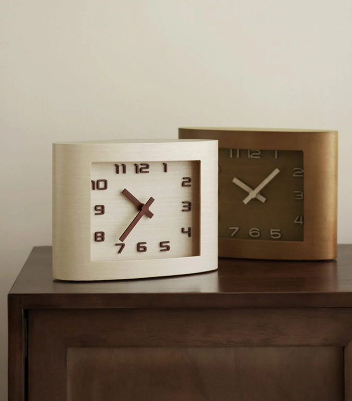 A close-up of a modern wall clock featuring a sleek design with a minimalist aesthetic. The clock is mounted on a light-colored wall, adding elegance to the decor